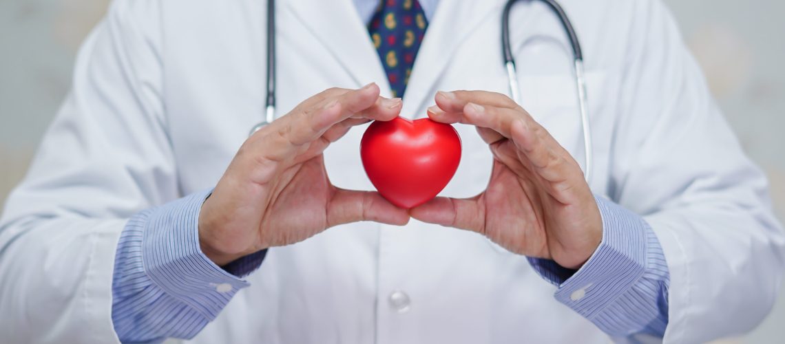 Doctor holding red heart in his hand in nursing hospital ward : healthy strong medical concept
